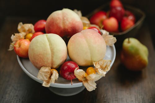 Free Delicious peaches apples and cape gooseberries on table Stock Photo