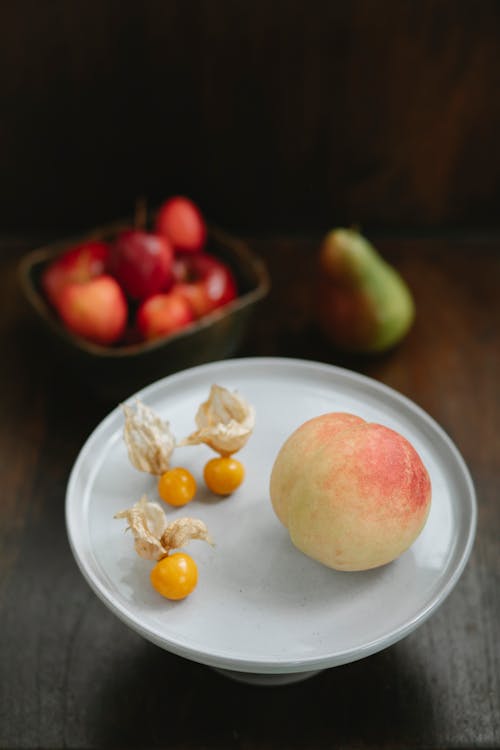 From above of fresh juicy peach and ripe amber cape gooseberries on white stand on table