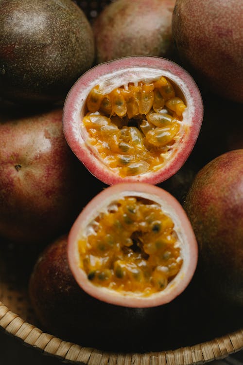 High angle of halves of fresh juicy passion fruits with yellow pulp in wicker bowl