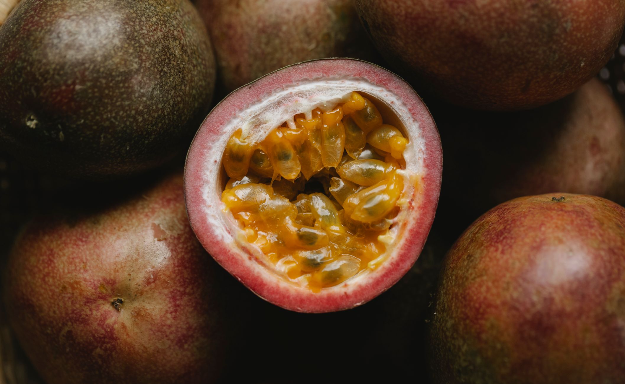 Closeup of ripe juicy halve of passion fruit with yellow flesh on heap of passion fruit