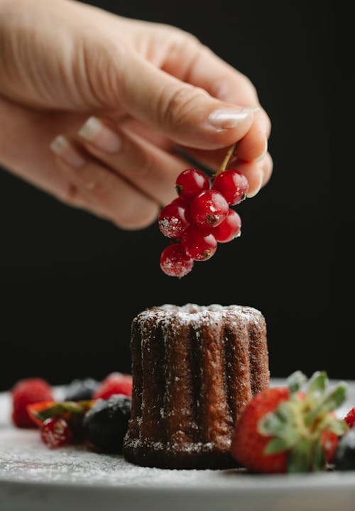 Free Crop faceless woman decorating cake with currant Stock Photo