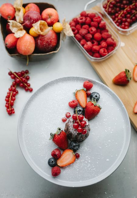 Top view of plate with chocolate fondant cake and blueberries with strawberry on table