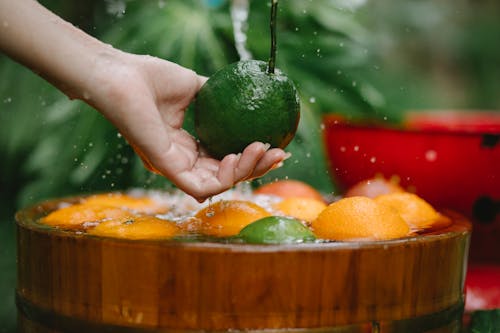 Crop woman washing fresh fruits in bowl