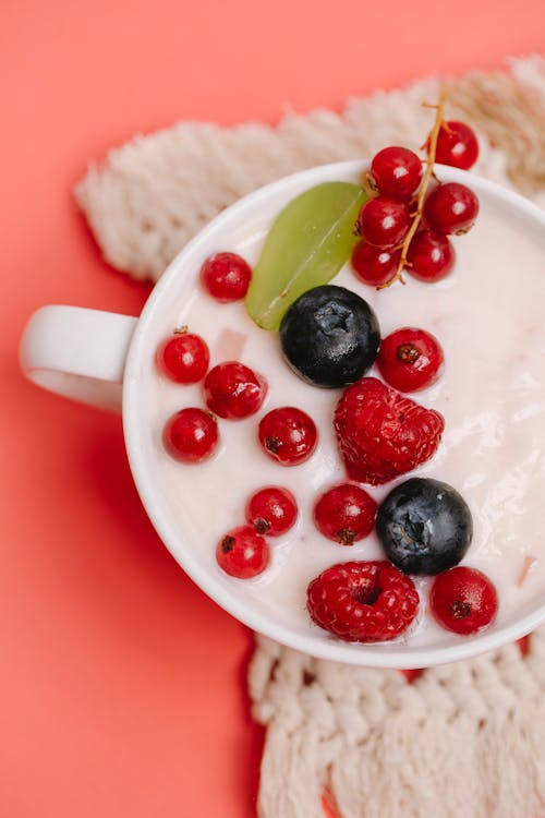 Free Top view of smoothie dessert with berries and yogurt served in cup on pink table in cafe Stock Photo