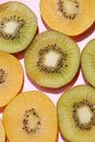 Top view of composed fresh tasty green kiwi slices placed on pink background