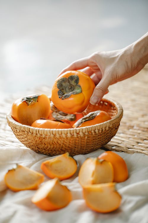 Personne Tenant Des Fruits Orange Sur Panier Tissé Marron
