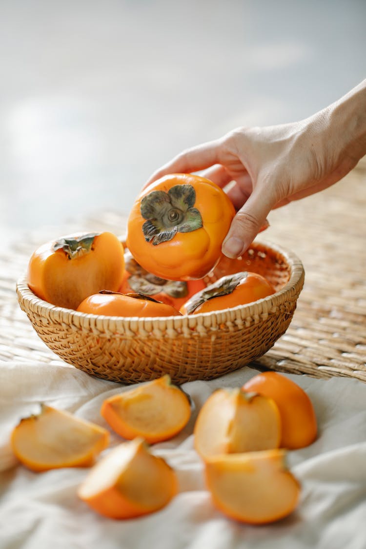 Crop Woman With Bowl Of Persimmons