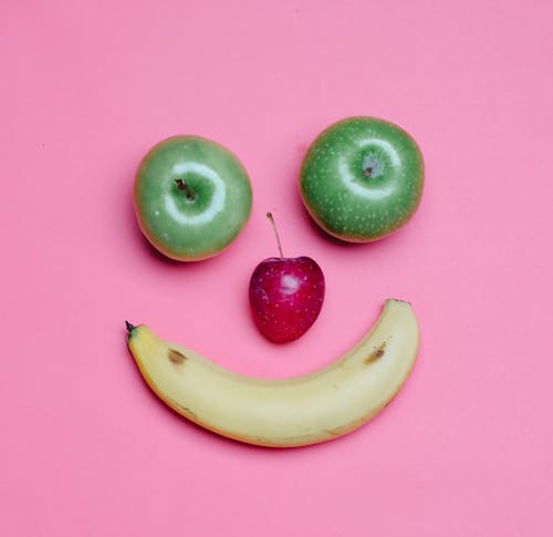 Free Top view of fresh ripe banana and green and red apples arranged as smile on pink background Stock Photo