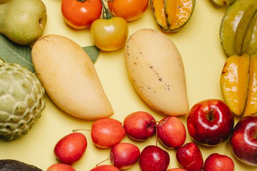 From above of assorted ripe fresh tasty healthy fruits placed on beige background