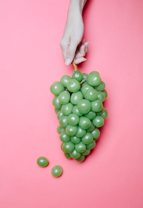 Crop woman demonstrating bunch of grapes