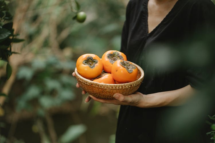 Crop Woman With Fresh Persimmons