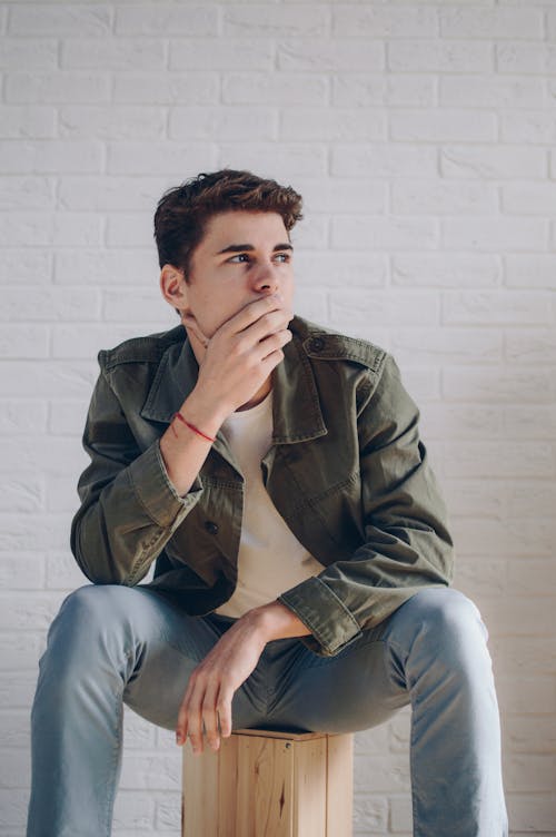 Man Wearing A Jacket Sitting On Brown Wooden Crate