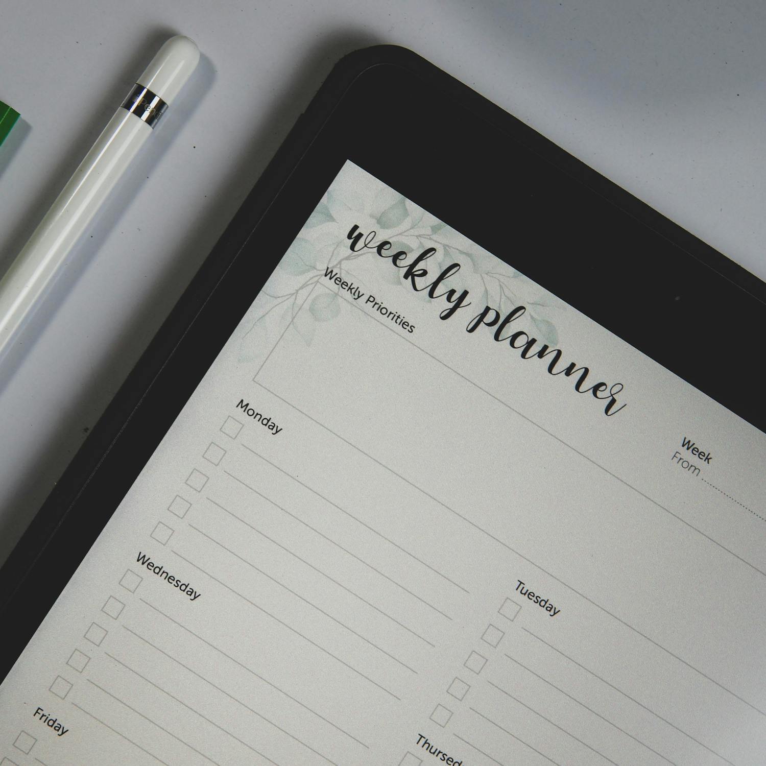 Top view of a digital tablet with weekly planner layout and stylus pen, ideal for organization.
