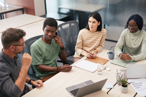 Free A diverse group of colleagues actively participating in a team meeting inside a modern office. Stock Photo