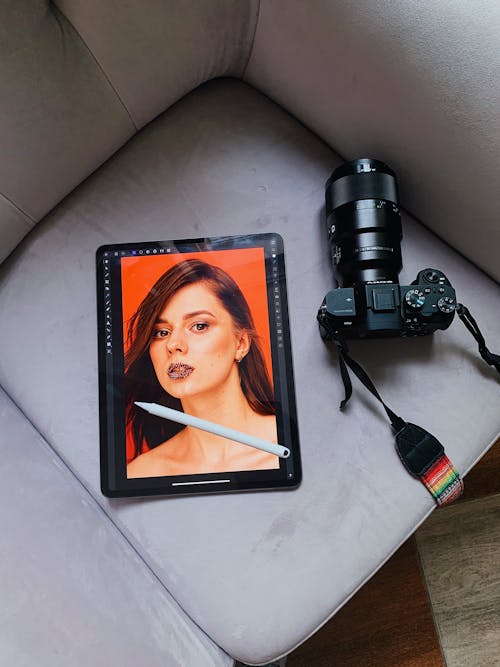 Free Close-Up Shot of a DSLR Camera beside a Tablet on a Sofa Stock Photo