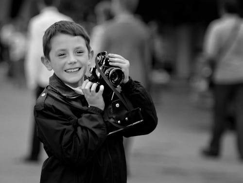 Grayscale Photo of a Boy Holding a Camera