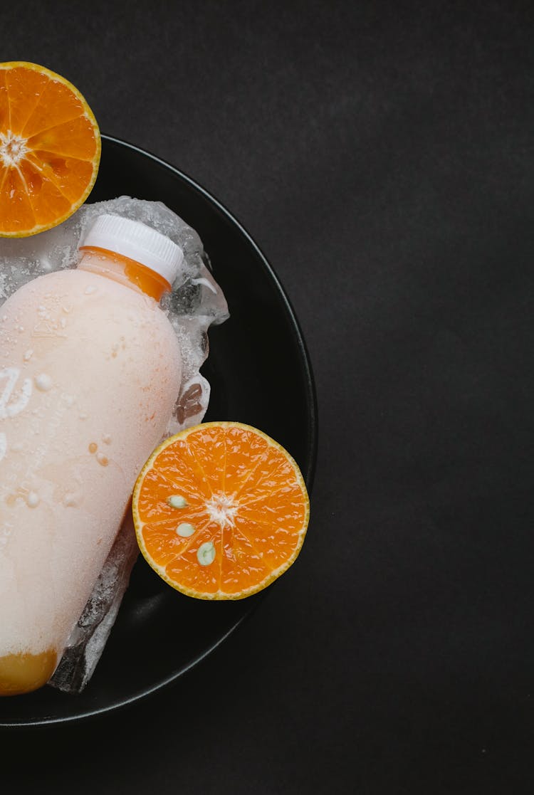 Cold Orange Juice Bottle In Bowl