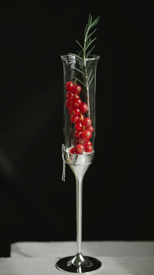 Ripe red currant berries placed in crystal flute glass on table against black background