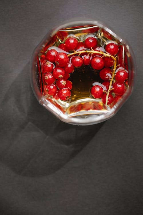 Glass with red berries on table