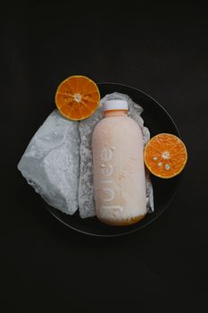 黑色背景上，冷冻的橙汁瓶旁点缀着冰和柑橘片，非常适合清爽的夏季时刻