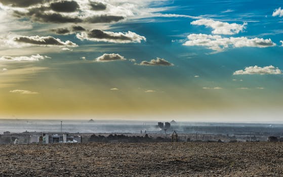 Scenic view of pyramids under a dramatic sky with light beams and clouds, capturing the essence of ancient Egypt.