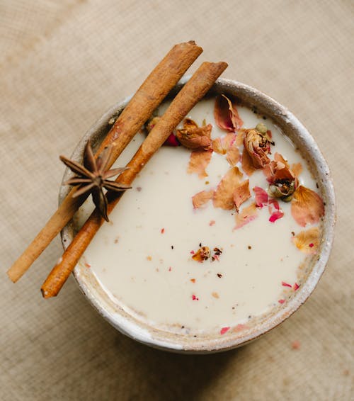Top view of traditional Indian tea with milk cinnamon sticks and star anise placed on blurred background in light kitchen
