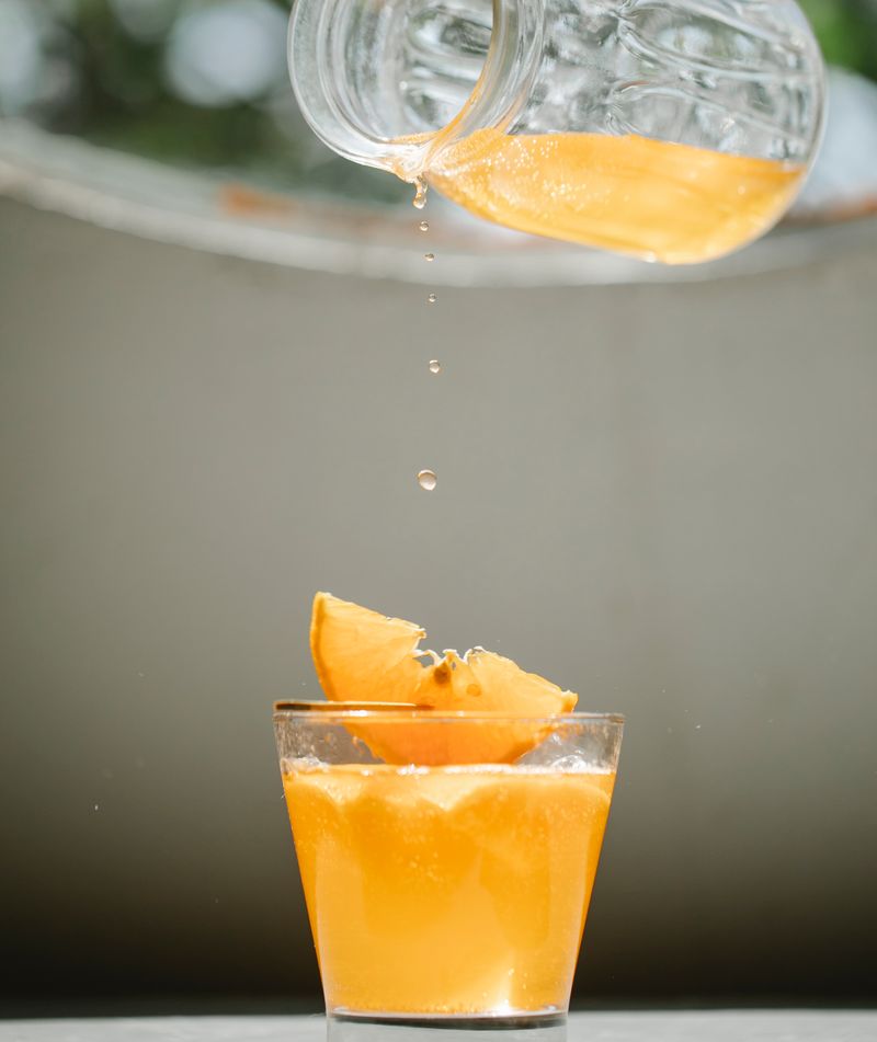 Glass of orange juice decorated with a citrus slice on a table.