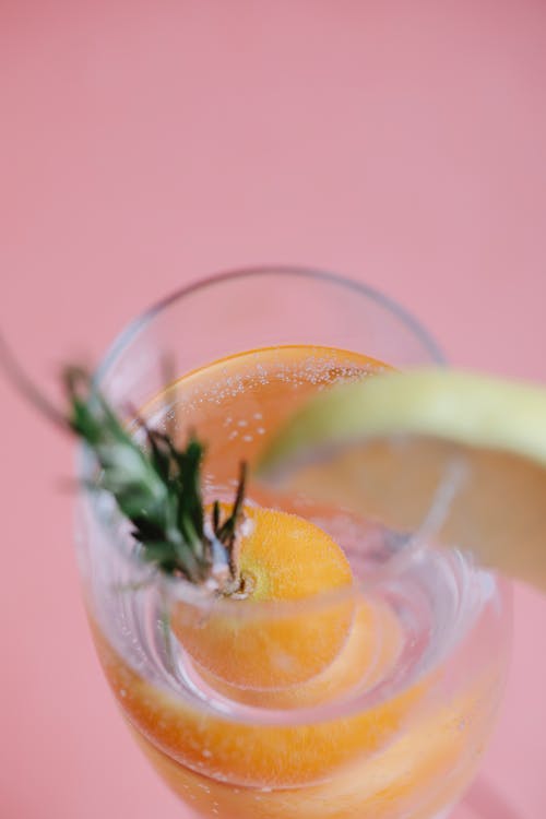 From above of fresh cold tasty drink with rosemary and kumquat on pink background