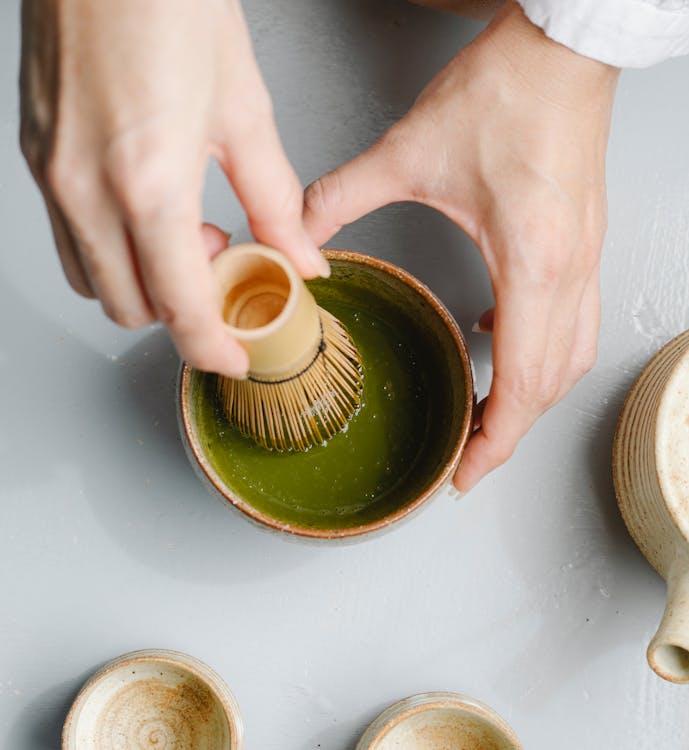 Free Top view of crop anonymous person using bamboo whisk while brewing hot matchaa tea ceremony Stock Photo