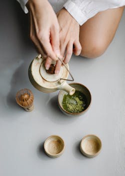 Overhead view of a traditional matcha tea ceremony with ceramic cups and bamboo whisk.