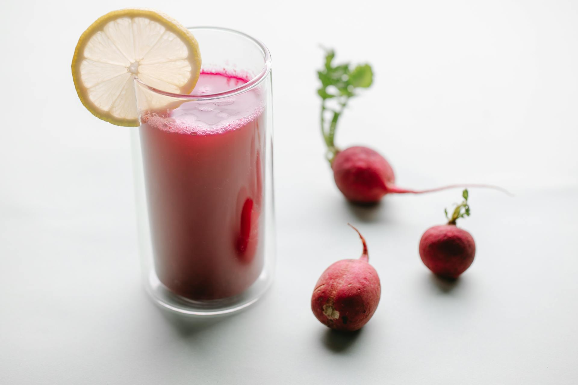 Fresh radish juice in glass with lemon slice, a healthy and vibrant detox drink.