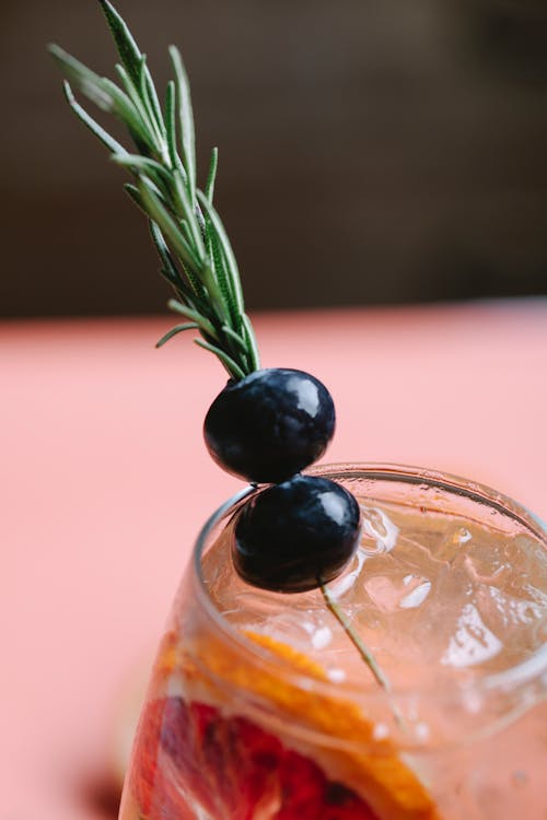 Glass of fresh cold tasty cocktail with red orange decorated with blueberry on blurred background