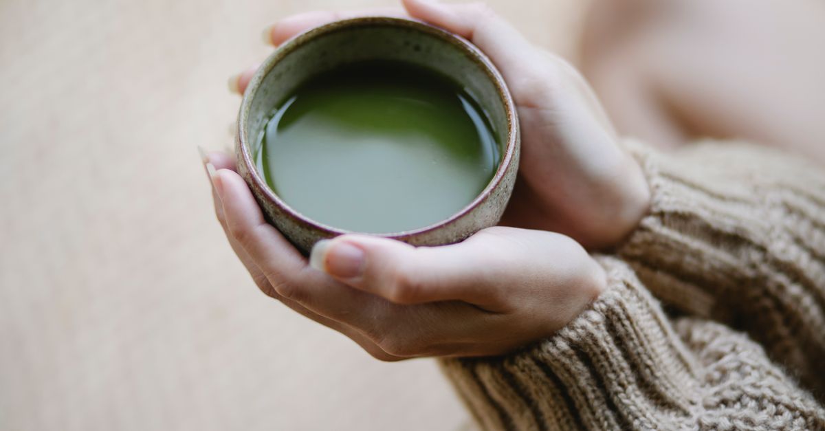 High angle of crop anonymous female in knitwear with ceramic cup of hot matcha tea - Evidence evidence guide for green tea stress randomized trial