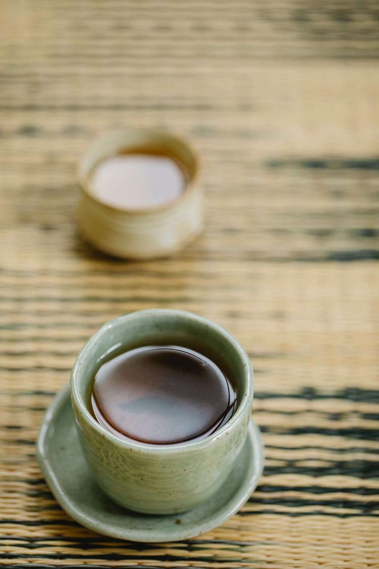 Ceramic Cups Of Tea On Straw Mat