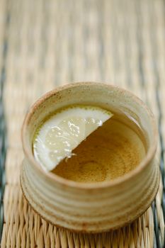 柳条垫上放着一个陶瓷茶杯，里面装满了热饮和柠檬片