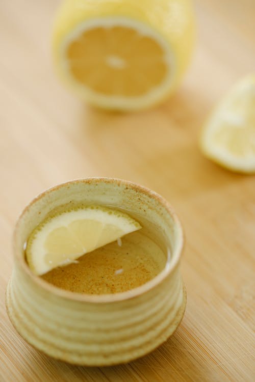 From above of oriental cup of green tea with aromatic juicy lemon slice on wooden table