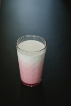 From above of transparent ornamental glass of tasty sweet protein milkshake on dark background