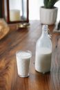 Ornamental glass near transparent bottle of creamy milk on table at home in daylight