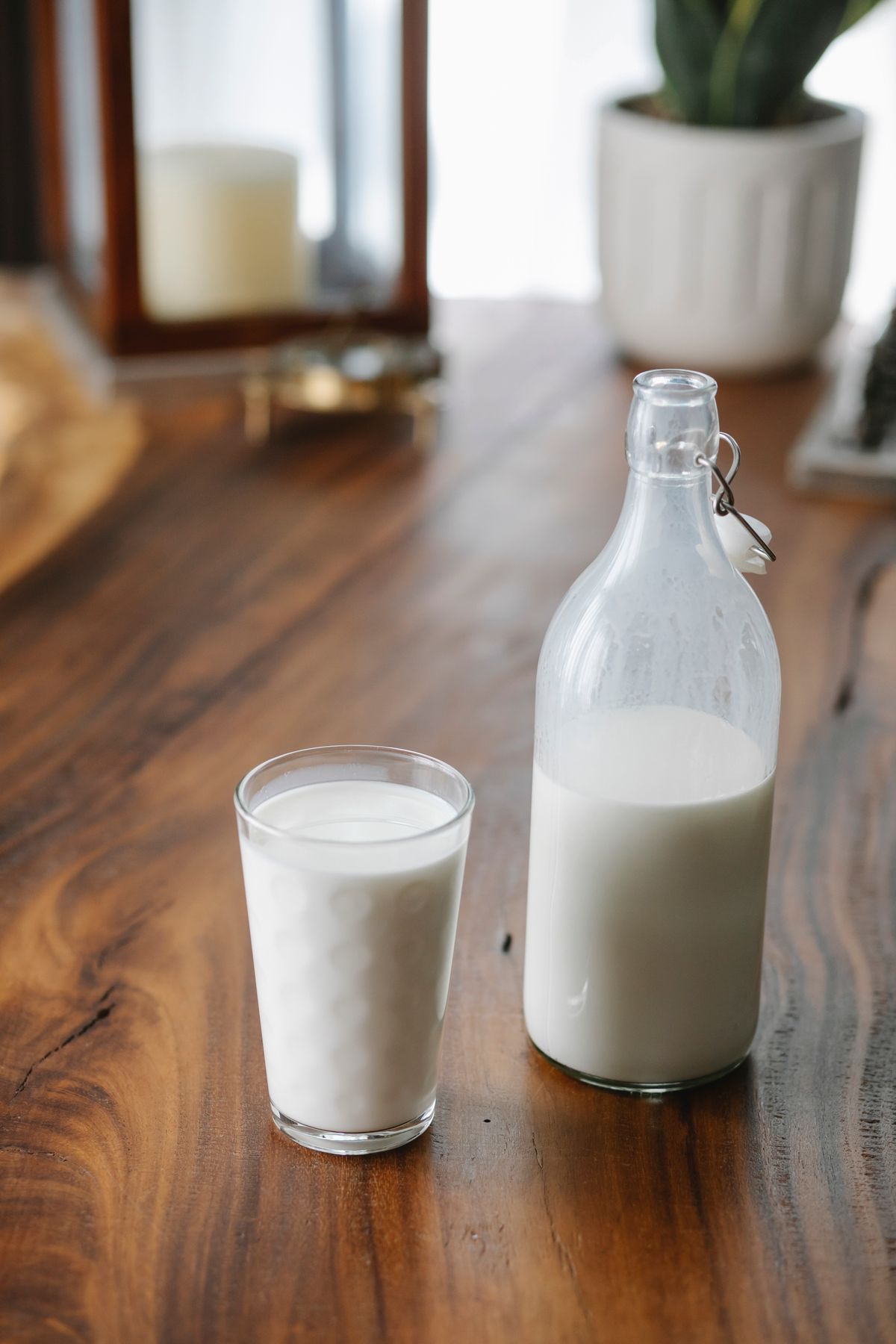 Fresh goat milk in an unbranded glass bottle and drinking glass