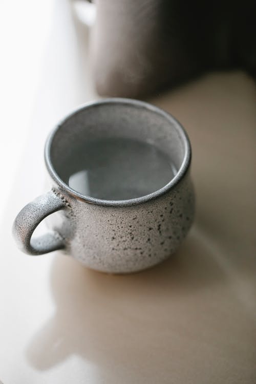 Free From above of rustic ceramic cup with boiled hot water prepared for tea and placed on table Stock Photo