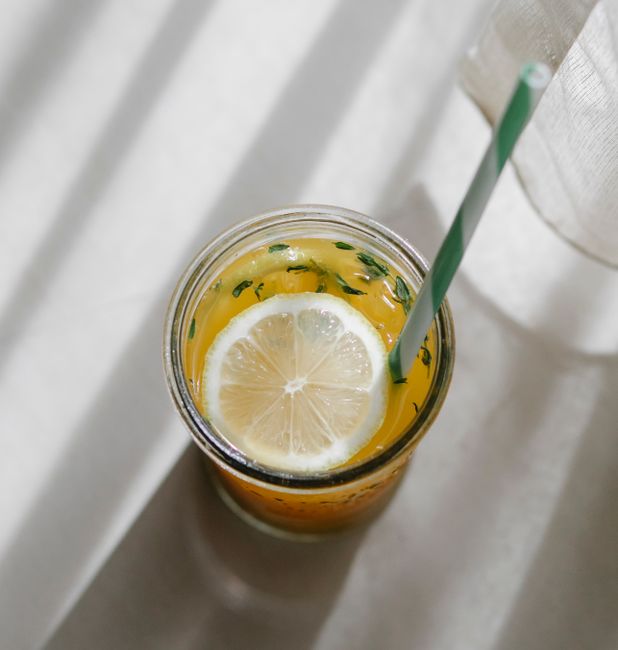 Top view of cold tasty homemade refreshing lemonade with straw in crystal glass