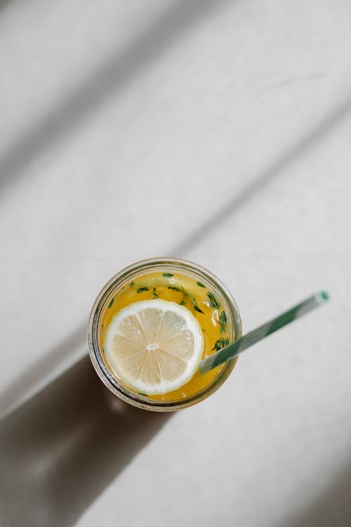 From above glass of cold refreshing homemade lemonade in crystal glass with slice of lemon and straw