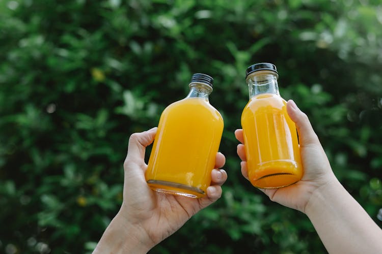 Crop Person With Bottles Of Juice