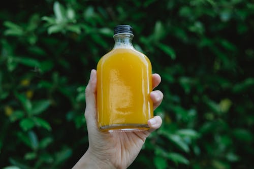 Free Crop person showing bottle of juice Stock Photo