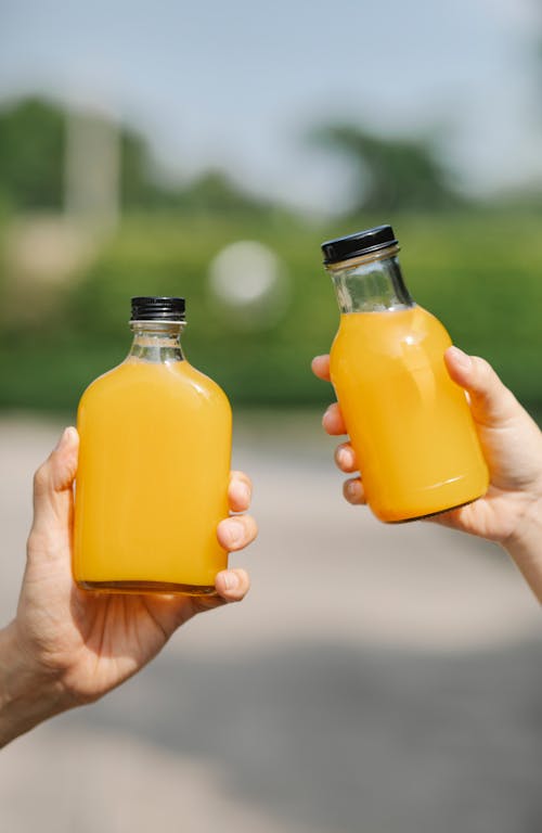 Free Crop people holding bottles with juice Stock Photo