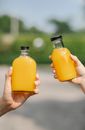Crop people holding bottles with juice