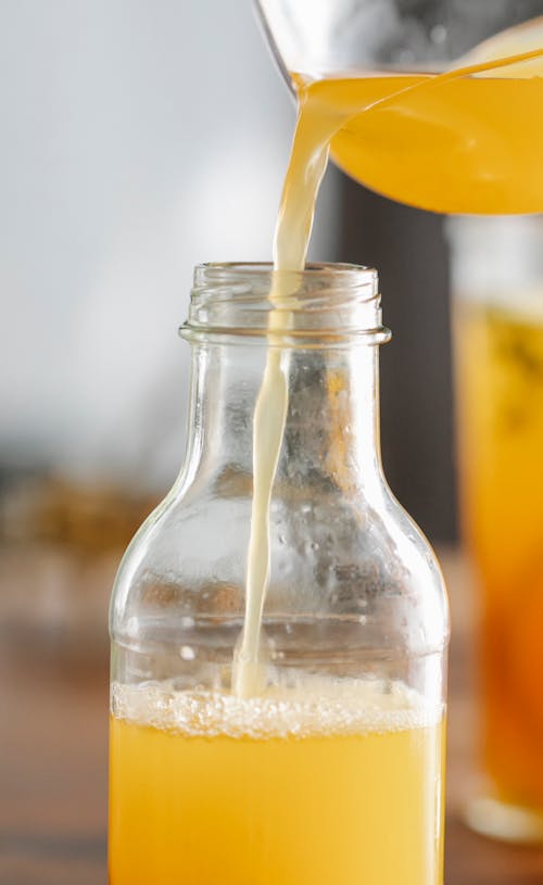 Crop person pouring fresh juice in bottle