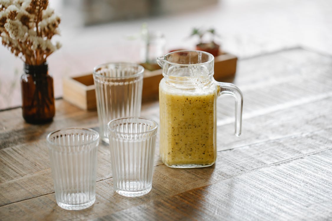 Free Jar with fresh tasty smoothie near empty glasses on wooden table in restaurant Stock Photo
