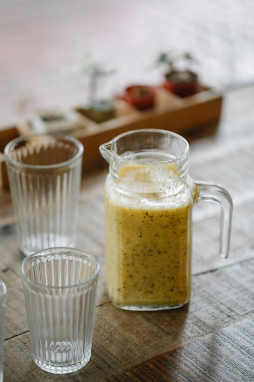 Free Jug with healthy vegan smoothie and transparent glasses on wooden table in cafe Stock Photo