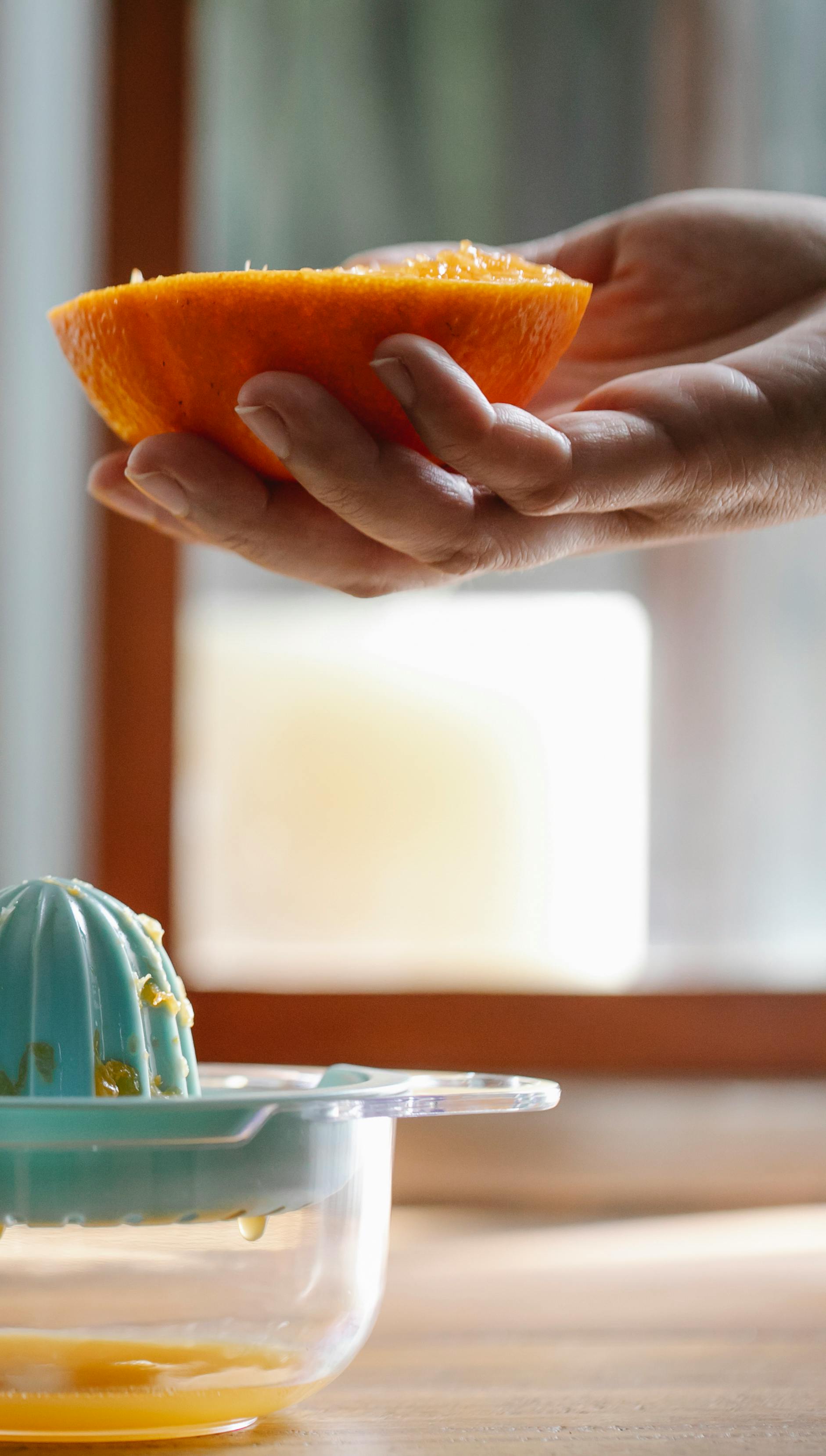 crop unrecognizable person squeezing orange juice in kitchen